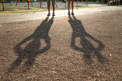 Low section of woman playing with shadow on ground