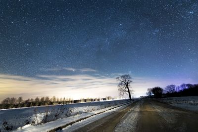 Road amidst snow field against sky at night