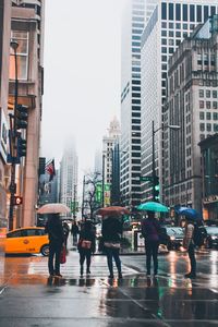 People walking on wet road in city during rainy season