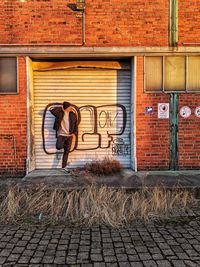 Full length of man standing on brick wall