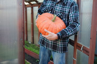 Midsection of man holding pumpkin while standing outdoors