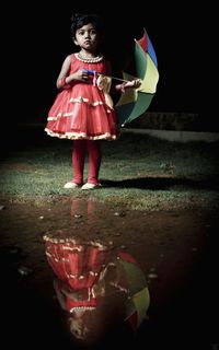 Girl holding umbrella with reflection in water