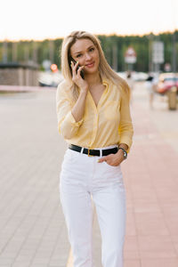 Happy young woman smiling and walking in the street talking on a smartphone person