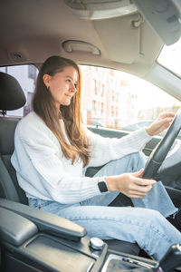 Young woman using phone while sitting in car