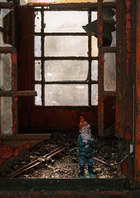 Rear view of boy standing by window