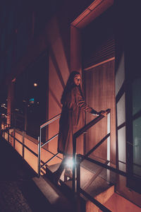 Woman standing by staircase at night