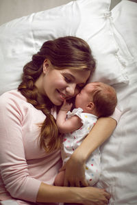 Mom with a small newborn daughter lying on the bed in the bedroom