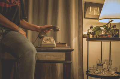 Midsection of woman holding telephone receiver at home