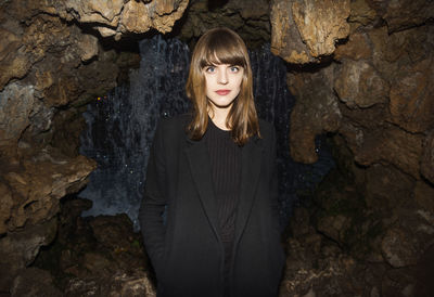 Portrait of young woman standing on rock formation