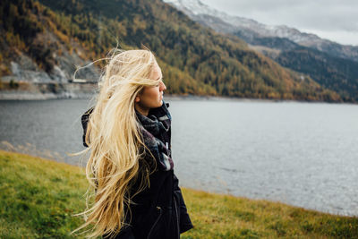 Beautiful woman standing by lake against sky