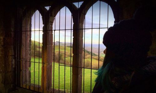 Rear view of woman looking through window