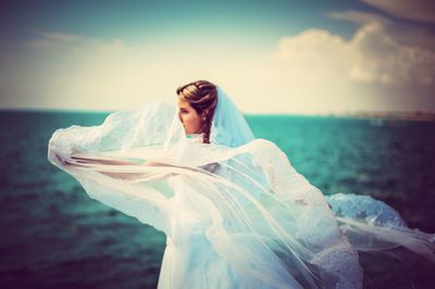 Young woman looking at sea shore against sky