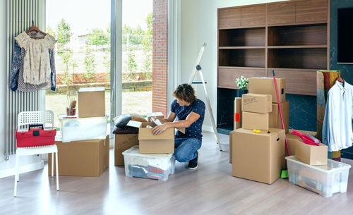Man reading paper while unpacking box at home