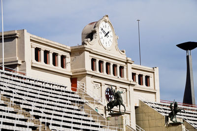 Low angle view of statue against empty stadium against sky