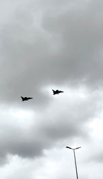 Low angle view of silhouette airplane against sky