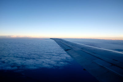 Airplane wing against sky during sunset