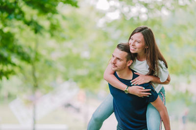 Man carrying woman on back while standing outdoors