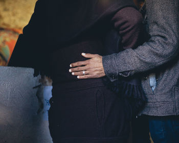 Midsection of couple holding hands at home