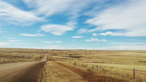 Road amidst field against sky