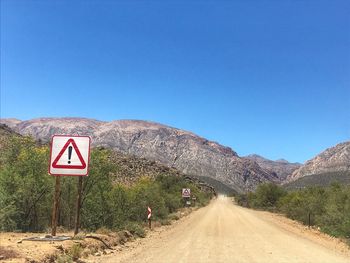 Road sign against clear blue sky