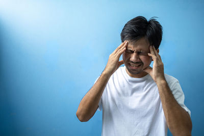 Portrait of man standing against blue background