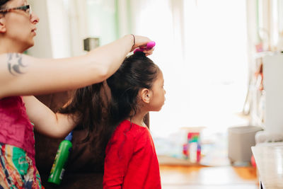 Mother combing daughters hair