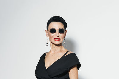 Young woman wearing sunglasses against white background