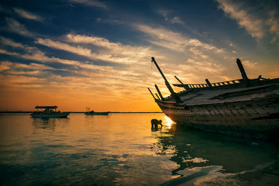 Fishing boat in sea against sky during sunset