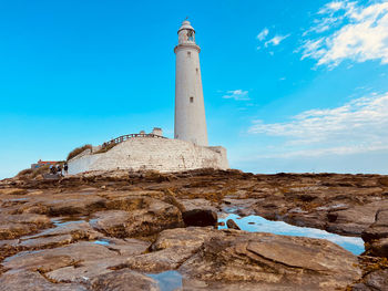 Lighthouse by sea against sky