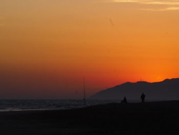 Scenic view of beach against orange sky