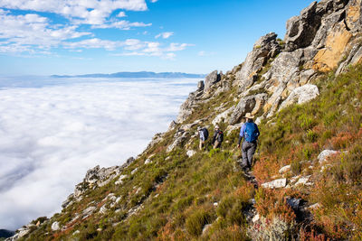 Rear view of man on rock against sky