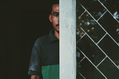 Portrait of man standing behind window