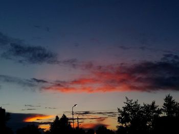 Low angle view of silhouette trees against dramatic sky