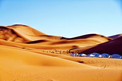 Sand dunes in desert against clear blue sky