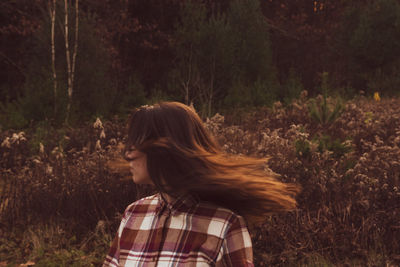 Woman wearing hat standing by plants in forest