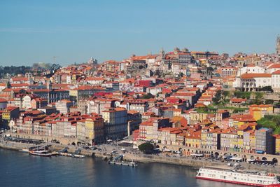 Aerial view of townscape by river against sky in city