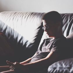 Close-up of young man sitting on sofa at home