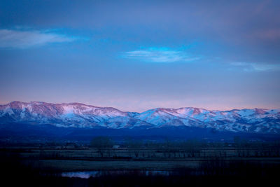 Scenic view of snowcapped mountains against blue sky