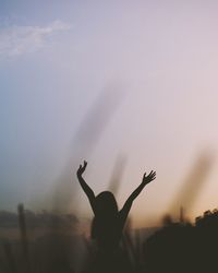Silhouette of man with arms raised against sky