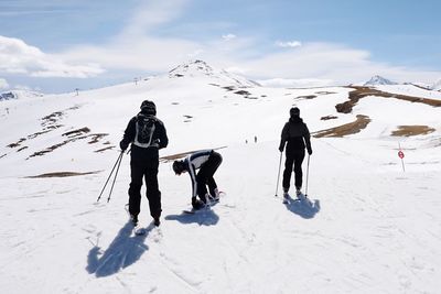 People on snow covered land against mountain and sky