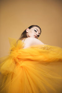 Close-up of young woman against yellow background