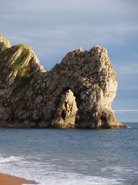 Rock formation in sea against sky