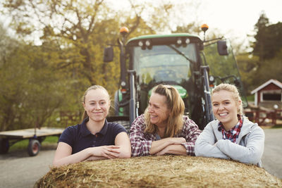 Smiling mother and daughters leaning on hay bale