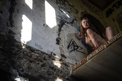 Low angle view of naked woman in abandoned room