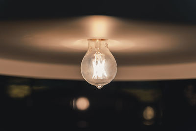 Close-up of light bulb hanging from ceiling