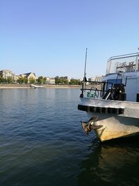 Boat moored on river against clear blue sky