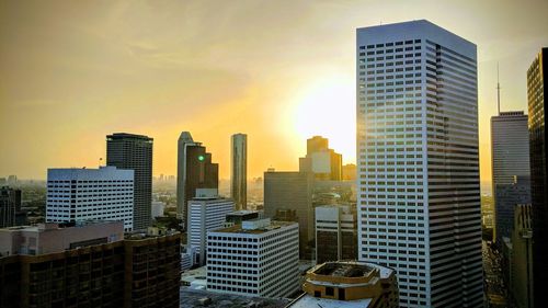 Modern buildings in city against sky during sunset