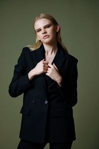 Portrait of young man standing against gray background