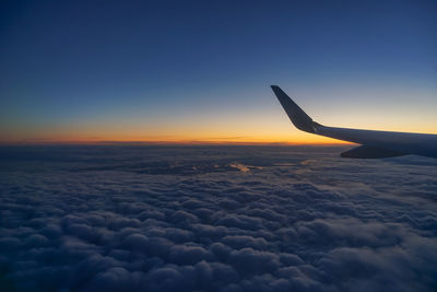 Airplane flying over cloudscape during sunset