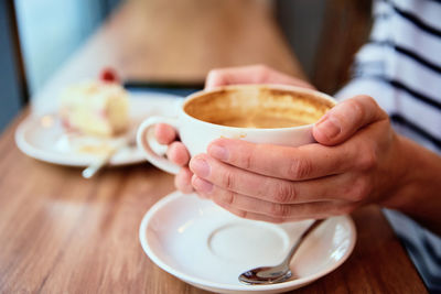 Woman have breakfast at cafe, hold coffee cap in hands